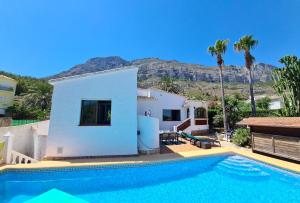 eine Villa mit einem Pool vor einem Haus in der Unterkunft 3 bedrooms villa with sea view private pool and furnished terrace at Denia 3 km away from the beach in Denia