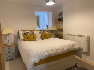 a bedroom with a bed with yellow pillows and a mirror at Neptune's Nook, Cromer in Cromer