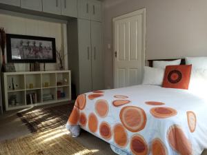 a bedroom with a large bed with an orange and white comforter at Tranquility by the sea in Cape Town