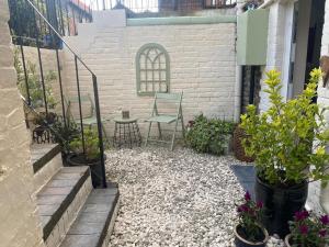 a patio with two chairs and a table and some plants at Neptune's Nook, Cromer in Cromer