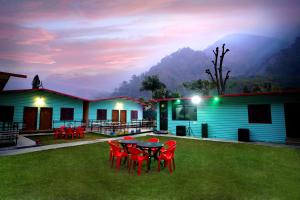 a patio with red chairs and a table in front of a house at Creek Forest - Riverside Boutique Resort in Rishīkesh