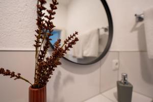 een vaas met bloemen in een badkamer met een spiegel bij Hotel Garni Moers in Moers