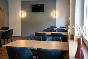 a room with tables and chairs and a tv on the wall at Hotel Garni Moers in Moers