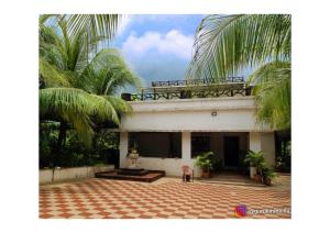 a house with palm trees in front of it at Dice Villa rooms in Alibaug