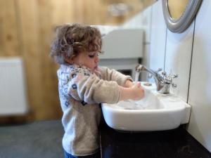 a young child is washing his hands in a sink at Le Vallon d'Armandine, gîte écologique Auvergne in Saint-Hilaire
