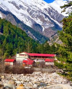 a building with a red roof next to a mountain at Misty Heaven in Harsil