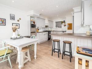 una cucina con armadi bianchi, tavolo e sgabelli di Pass the Keys Stylish Cosy 3Bed Family Friendly Home in Hatfield a Hatfield