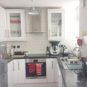 a kitchen with white cabinets and a stove top oven at Cosy studio flat, great location! in London
