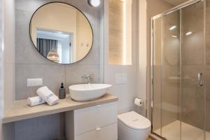 ein Badezimmer mit einem Waschbecken, einem Spiegel und einem WC in der Unterkunft Ambria Apartments Bałtycki in Świnoujście