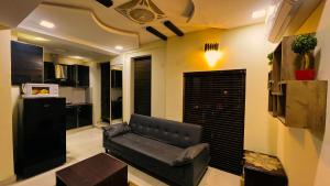 a living room with a leather couch and a kitchen at LMY Residency - Bahria Town Lahore in Lahore