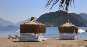 two straw umbrellas and chairs on a beach at Marti Resort Deluxe Hotel in Marmaris