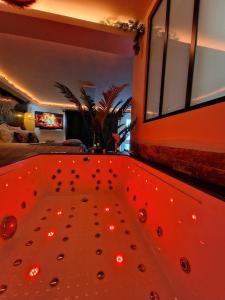 - un bain à remous avec des lumières rouges dans la chambre dans l'établissement Loveroom Jungle Love Proche Disneyland, à Serris