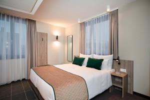 ein Hotelzimmer mit einem großen Bett mit grünen Kissen in der Unterkunft Leonardo Hotel Vienna City West in Wien