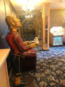 Una statua di un uomo seduto su una sedia in una stanza di Hotel Eulenspiegel - Das Erlebnishotel in Riesa a Riesa