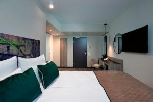 una camera d'albergo con un grande letto e una TV a schermo piatto di Leonardo Hotel Vienna Otto-Wagner a Vienna