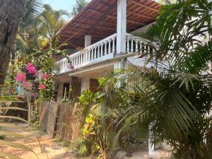 a house with a porch with a fence and plants at Palm Breeze Suites in Palolem