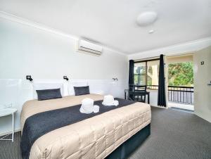 a bedroom with a large bed with two hats on it at Kandos Fairways Motel in Kandos