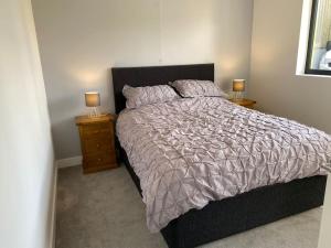 a bedroom with a bed and two night stands with lamps at Cedar Garden Cottage in East Chinnock