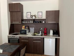 uma cozinha com armários castanhos, um lavatório e uma mesa em Мия 3 Спа хотел Свети Спас em Velingrad