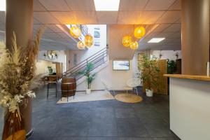 a lobby with chairs and tables and stairs at Résidence Otellia in Blanquefort