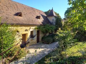 een oud stenen gebouw met een deur en een tuin bij Domaine du Fraysse L'Ermitage un coin de paradis in Saint-Cybranet