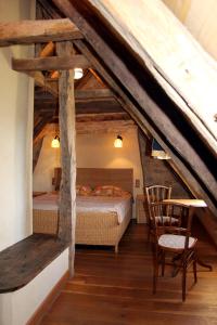 a attic bedroom with a bed and a table and chairs at Domaine du Fraysse L'Ermitage un coin de paradis in Saint-Cybranet