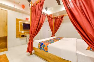 a bedroom with red curtains and a bed and a tv at FabHotel Apollo in Naroda
