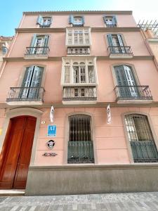 um edifício cor-de-rosa com janelas e varandas numa rua em Tennessee Urban Suites em Málaga