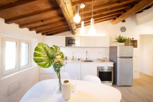 ルッカにあるSibilla Luxury Flat in center townの花瓶に花が飾られたテーブルのあるキッチン