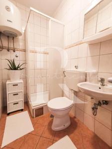 Apartments Rukelj في كارلوباغ: حمام ابيض مع مرحاض ومغسلة