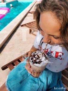 een jong meisje dat een drankje drinkt met een milkshake bij Apartments Rukelj in Karlobag