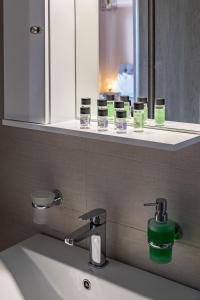 un lavabo de salle de bain avec un miroir et un distributeur de savon vert dans l'établissement Iliana Apartments, à Tolón 148 autres photos