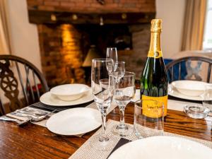 a bottle of wine sitting on a wooden table with glasses at Pass the Keys Malt House With Hot Tub Stunning Tudor Cottage in Craven Arms