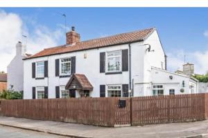 a white house with a fence in front of it at Cosy Cottage in Knottingly