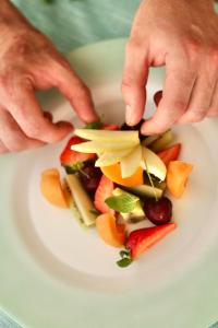 a person cutting up fruit on a white plate at Hotel Flora in Cattolica
