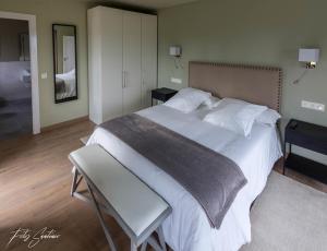 a bedroom with a large white bed and a chair at Apartamentos Buenavista Tineo in Tineo