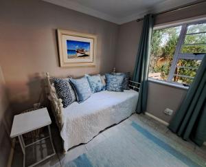a bedroom with a bed with blue pillows and a window at Ocean Song in Van Stadensriviermond