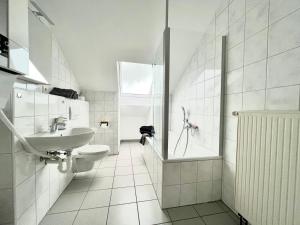 a bathroom with a sink and a toilet and a shower at favstay Industrialstyle 2-Zimmer 60qm mit Balkon, Panarbora Fernblick, 55" TV & Netflix, 55Mbit WLAN, Parkplatz in Waldbröl
