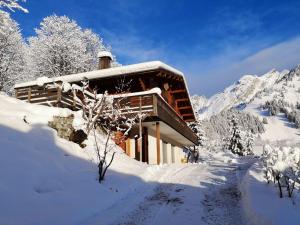 uma cabana de madeira na neve com montanhas ao fundo em Appartement La Clusaz, 4 pièces, 6 personnes - FR-1-304-214 em La Clusaz