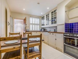 a kitchen with white cabinets and a table and chairs at Pass the Keys Charming Old Coastguards Cottage in Chichester