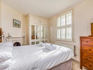 sypialnia z dużym białym łóżkiem i komodą w obiekcie Pass the Keys Charming Old Coastguards Cottage w mieście Chichester