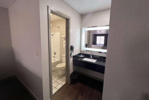 a bathroom with a sink and a toilet and a mirror at Days Inn & Suites by Wyndham - Canton First Monday Trade Days in Canton