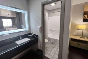 a bathroom with a sink and a toilet and a mirror at Days Inn & Suites by Wyndham - Canton First Monday Trade Days in Canton
