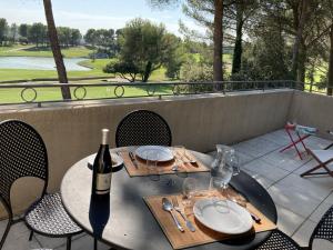 una mesa con una botella de vino en el patio en Magnifique Vue CLIM LINGE Golf Saumane 6P Piscine Tennis en Saumane-de-Vaucluse