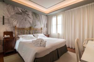 1 dormitorio con 1 cama grande con sábanas blancas en Terme Preistoriche Resort & Spa, en Montegrotto Terme