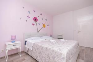 a bedroom with a bed with a flower and butterflies on the wall at Spacious apartment Snowwhite Split in Split