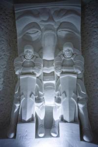a white sculpture of two people sitting on a bench at Lapland Hotels SnowVillage in Kittilä