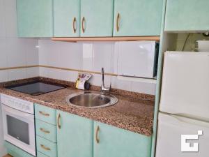 una pequeña cocina con fregadero y nevera. en Apartamento Amatista 29A - Grupo Turis, en Calpe