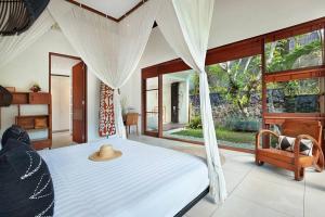 a bedroom with a white bed and a large window at Villa Bengawan in Canggu