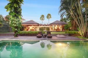 a house with a swimming pool in front of a house at Villa Bengawan in Canggu